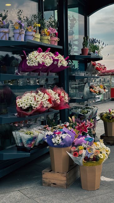 A display of fresh floral arrangements at a florist shop near Angel station, Finsbury, featuring various bouquet styles with white, pink, and purple flowers, wrapped in colorful paper and placed on sh