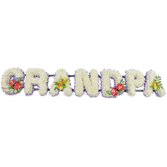 Set against a simple white background, this bespoke funeral flower tribute spells out "GRANDPA" in large, three-dimensional capital letters, joined in a continuous horizontal display. Each letter is meticulously covered in small, snow-white chrysanthemums, packed closely together to form a plush, textured surface that looks both full and comforting, like a soft blanket of petals. The flowers are fresh and uniform, giving the word a clean, crisp silhouette that stands out clearly in photographs or beside a coffin during a service. Trimming the base of each letter is a narrow band of pale lavender ribbon, just visible beneath the blooms. This subtle touch of colour provides gentle definition, creating a soft border that complements the white rather than competing with it. Behind the letters, a dark green framework supports the arrangement, mostly hidden but occasionally glimpsed between the blooms, offering a natural contrast and hinting at the careful mechanics that keep the tribute secure for delivery across Finsbury and the surrounding area. Thoughtfully positioned accent sprays bring added character and meaning. On the "G" and "D", clusters of deep red anthuriums with their glossy, heart-shaped spathes and prominent golden spadices nestle among lush green foliage and tiny filler flowers, drawing the eye and symbolising devotion and remembrance. On the first "A" and the final "A", sprays of yellow-green orchids sweep gracefully across the chrysanthemums, their delicate petals and speckled throats conveying elegance and enduring love. This personalised "GRANDPA" tribute is the kind of arrangement chosen by families wanting a named memorial that feels both classic and heartfelt, suitable for a funeral, memorial service, or graveside gathering for a much-loved grandfather.