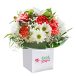 This lush bouquet, perfectly poised in a crisp white gift bag, seems to capture the uplifting spirit of a bright Finsbury morning. Soft coral and vivacious red carnations, with their frilly, textured petals, bloom alongside snowy white daisies, each glowing with a lime-hued centre that draws the eye and warms the heart. Fine sprigs of airy baby's breath drift through the arrangement, bringing a cloudlike softness, while hints of unopened, purple-tinged buds nestle quietly to the side, whispering of promises yet to come. Encircling the blooms, deep verdant leaves arch gracefully, grounding the bouquet and echoing the tranquil greenery of local parks. The sturdy white bag, fitted with gentle ribbon handles, not only cradles the flowers but also adds a modern touch for easy gifting-whether to a home along Rosebery Avenue or a friend by City Road. Against the pristine white background, each colour and texture stands vividly, evoking both celebration and sincerity. This bouquet reflects expert local craftsmanship-a thoughtful way to brighten a birthday, mark an anniversary, or simply bring a smile somewhere in Finsbury.